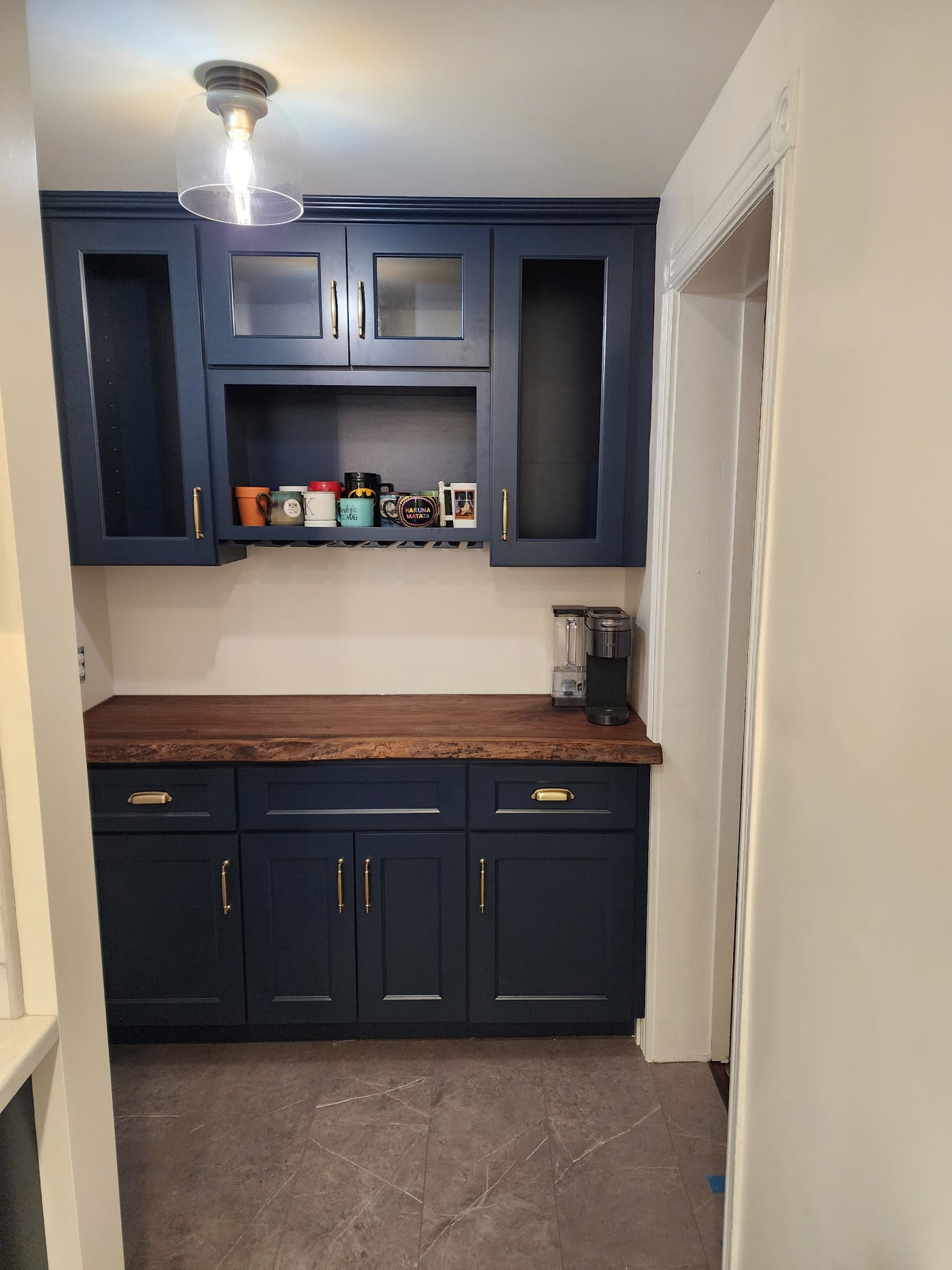 Kitchen with blue cabinets, wooden countertop, and coffee maker.