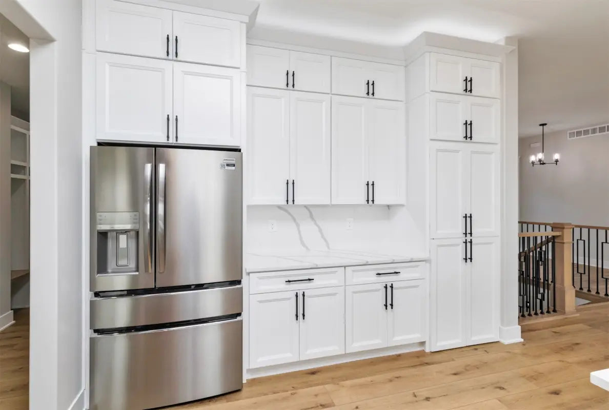 Modern white kitchen cabinets with stainless steel refrigerator.