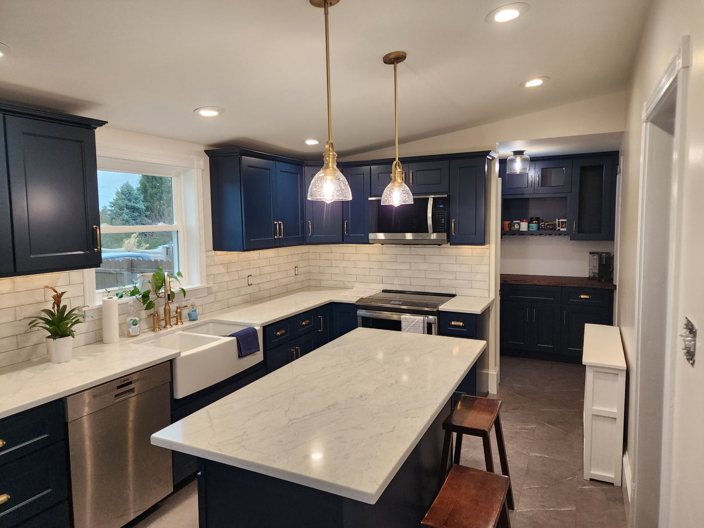 Modern kitchen with blue cabinets, white countertops, and stainless steel appliances.